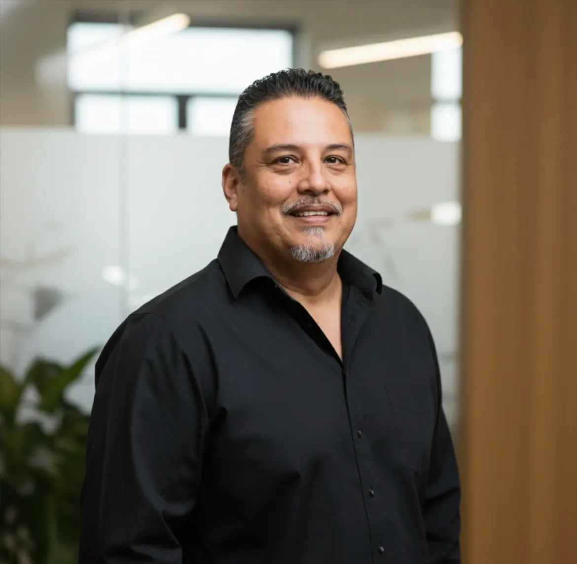 Milo Salazar, owner of Source Roofing, smiling in a professional office setting