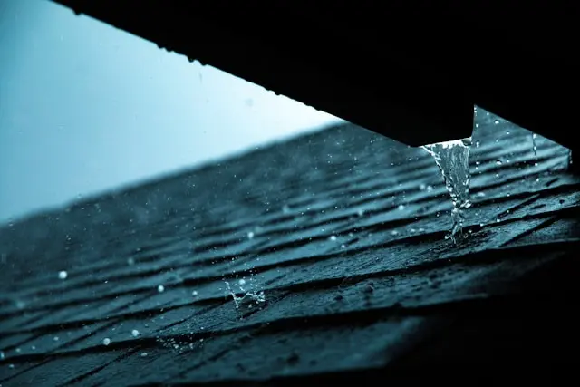 Roofer inspecting a residential roof for leaks and damage