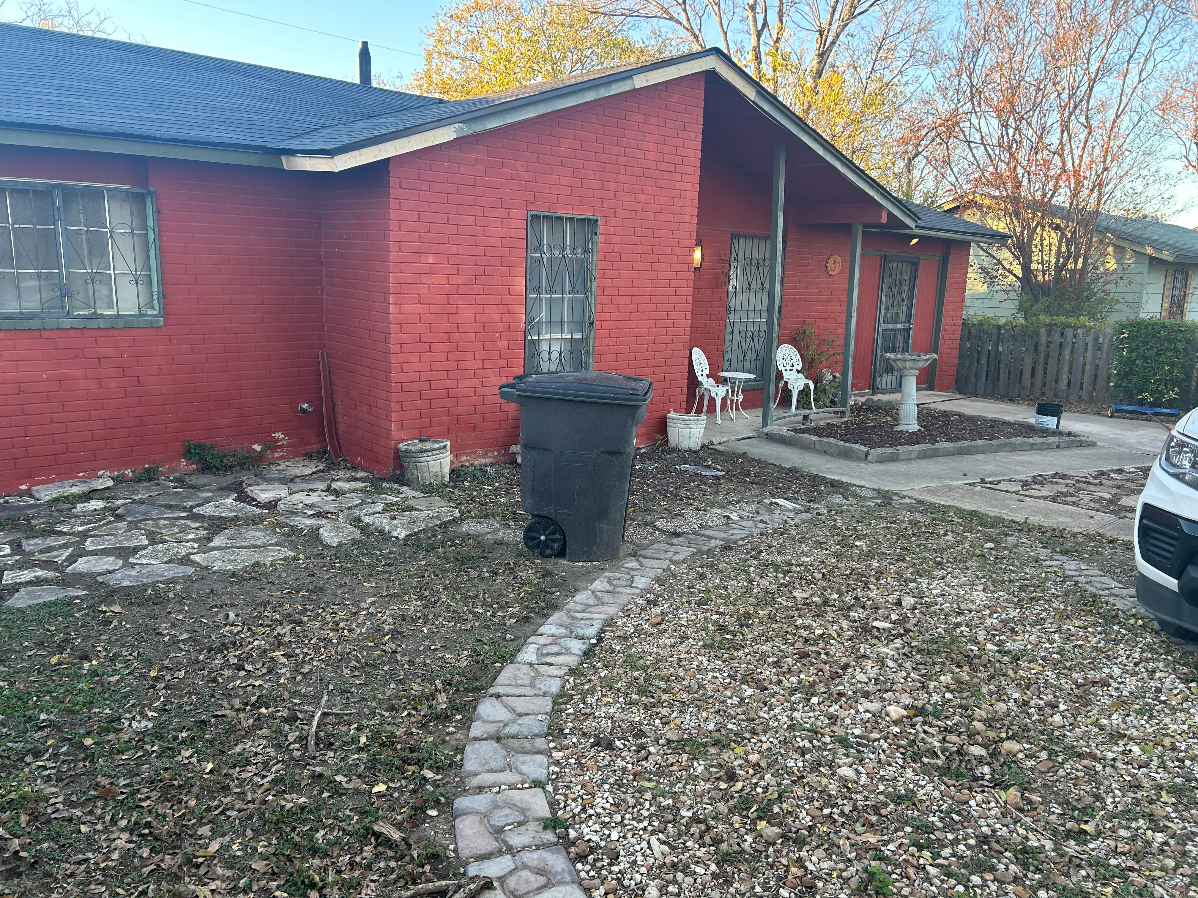 After: dark gray asphalt shingle roof with new ridge caps, seen from the roof; crew boots and ladder at the top edge of the frame.