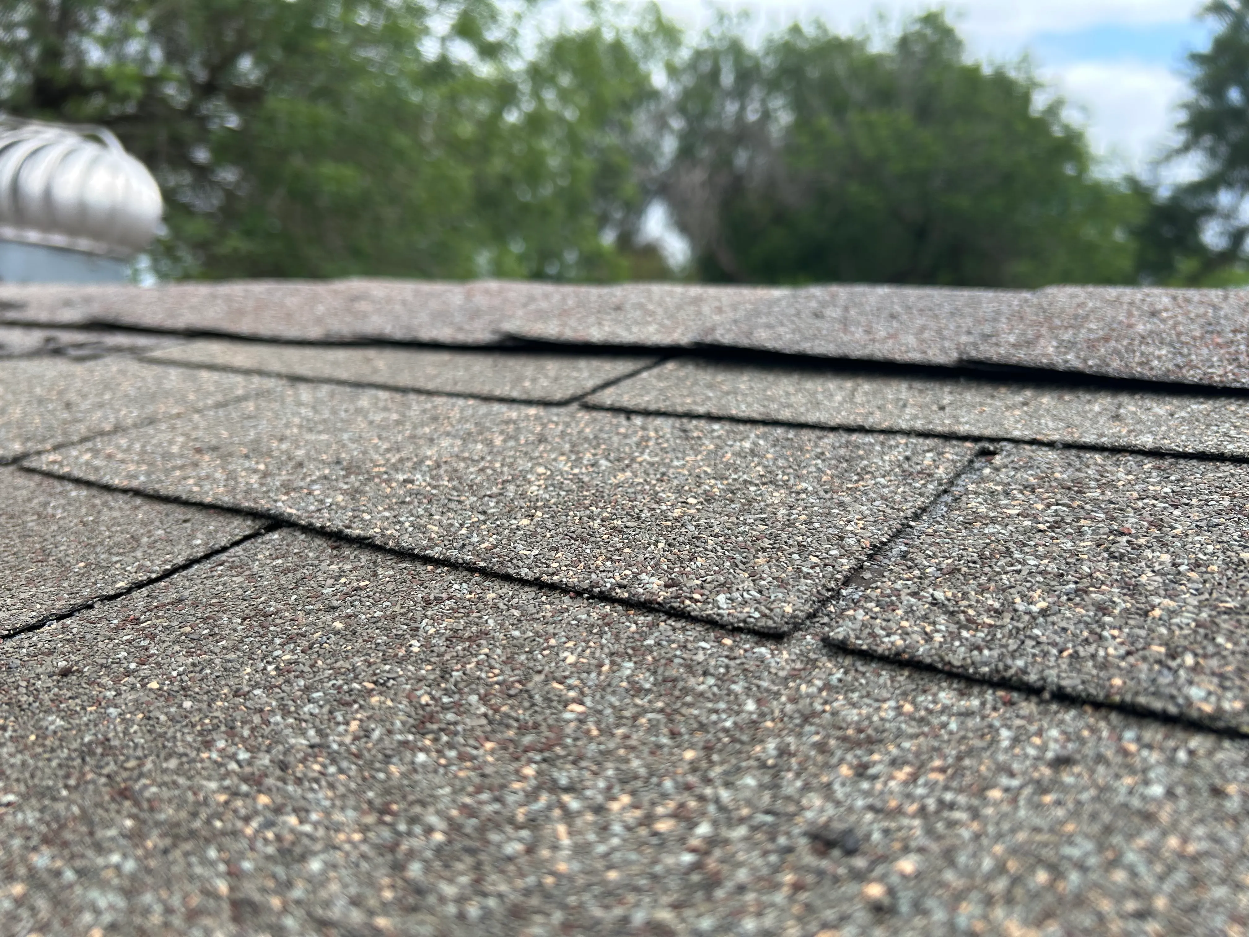 After: close-up of brown and gray architectural shingles with even granule coverage and sealed laps.