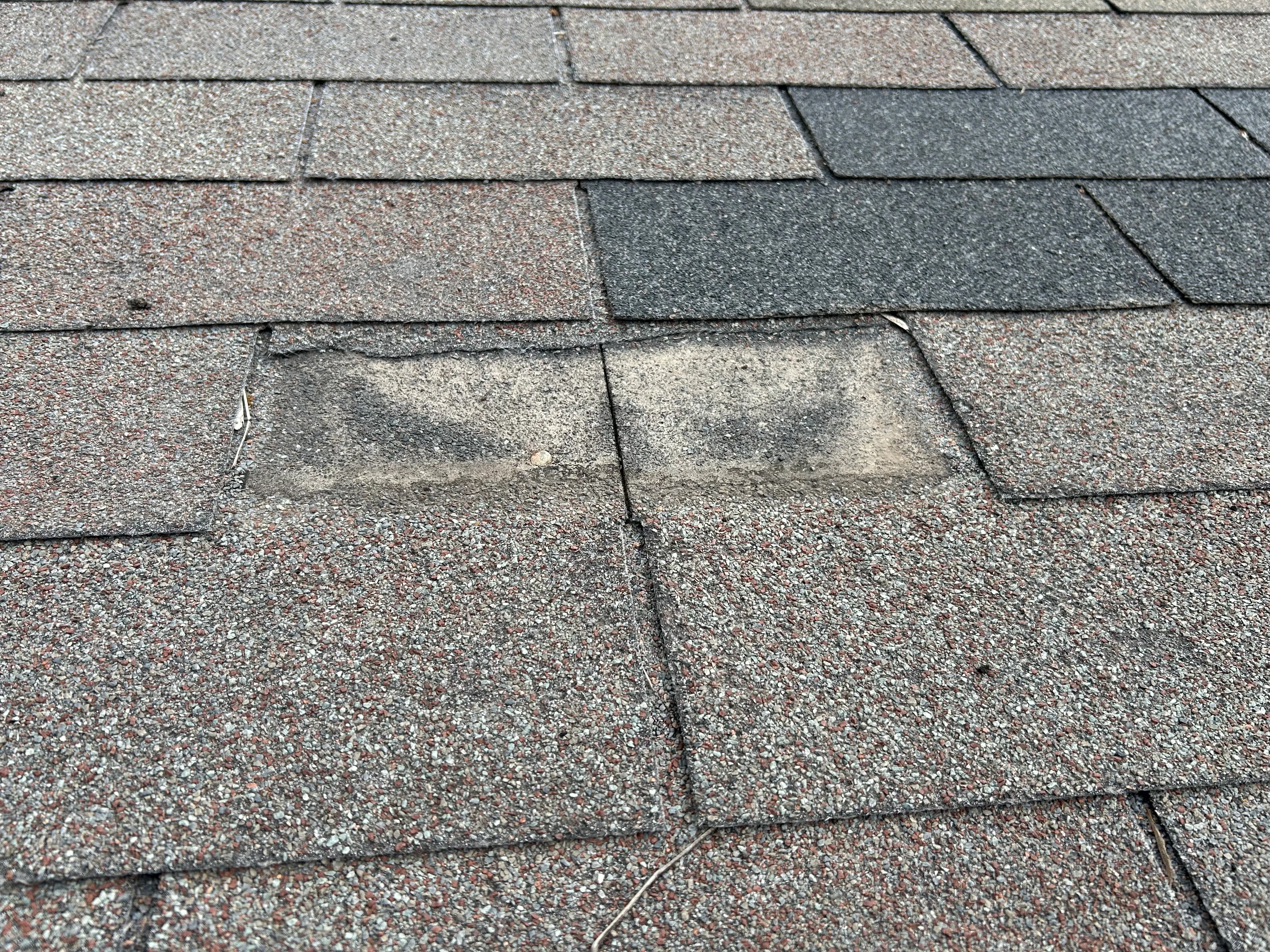 Before: close-up of asphalt shingles with two tabs that lost granules, exposing the mat beneath.